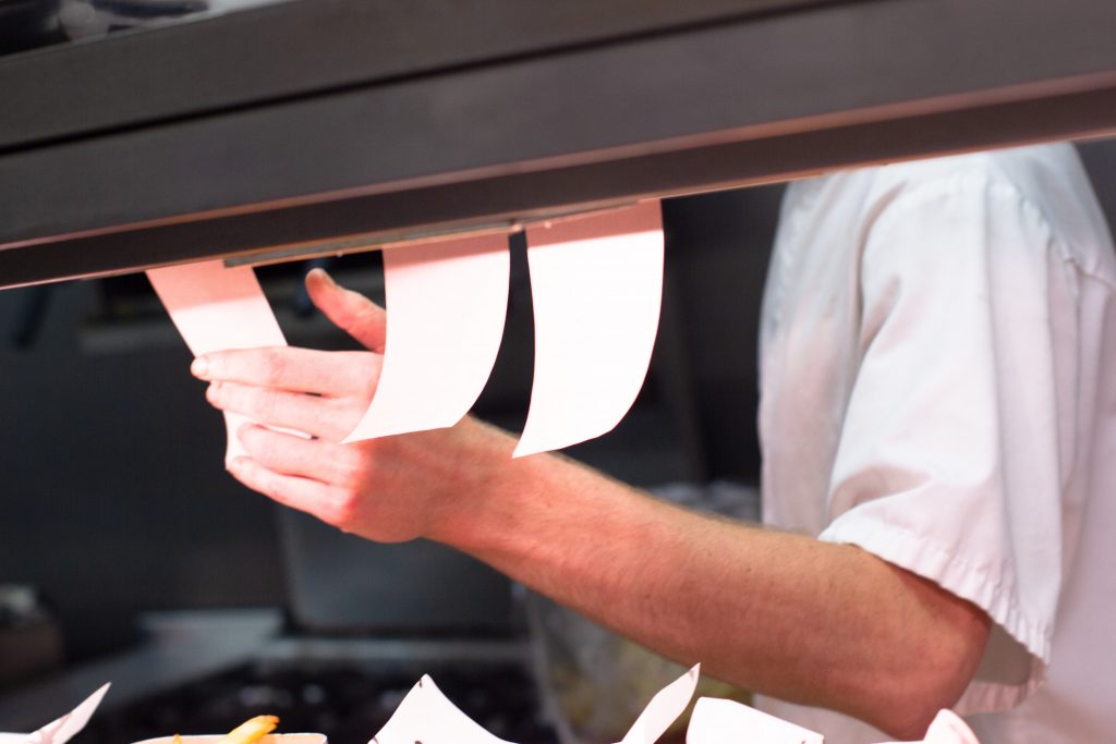 Cuisinier qui saisit les notes de commande dans une cuisine professionnelle.