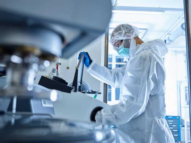 Laborantin en combinaison dans une salle blanche pour utiliser une machine spéciale