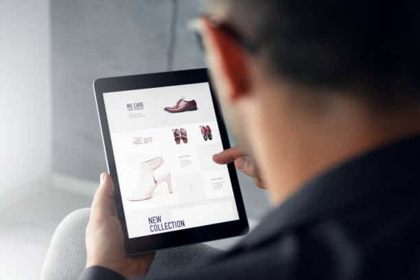 Homme qui regarde un site de chaussures en ligne sur une tablette numérique