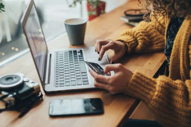 Femme qui entre ses données bancaires sur un site e-commerce, à partir de son ordinateur portable